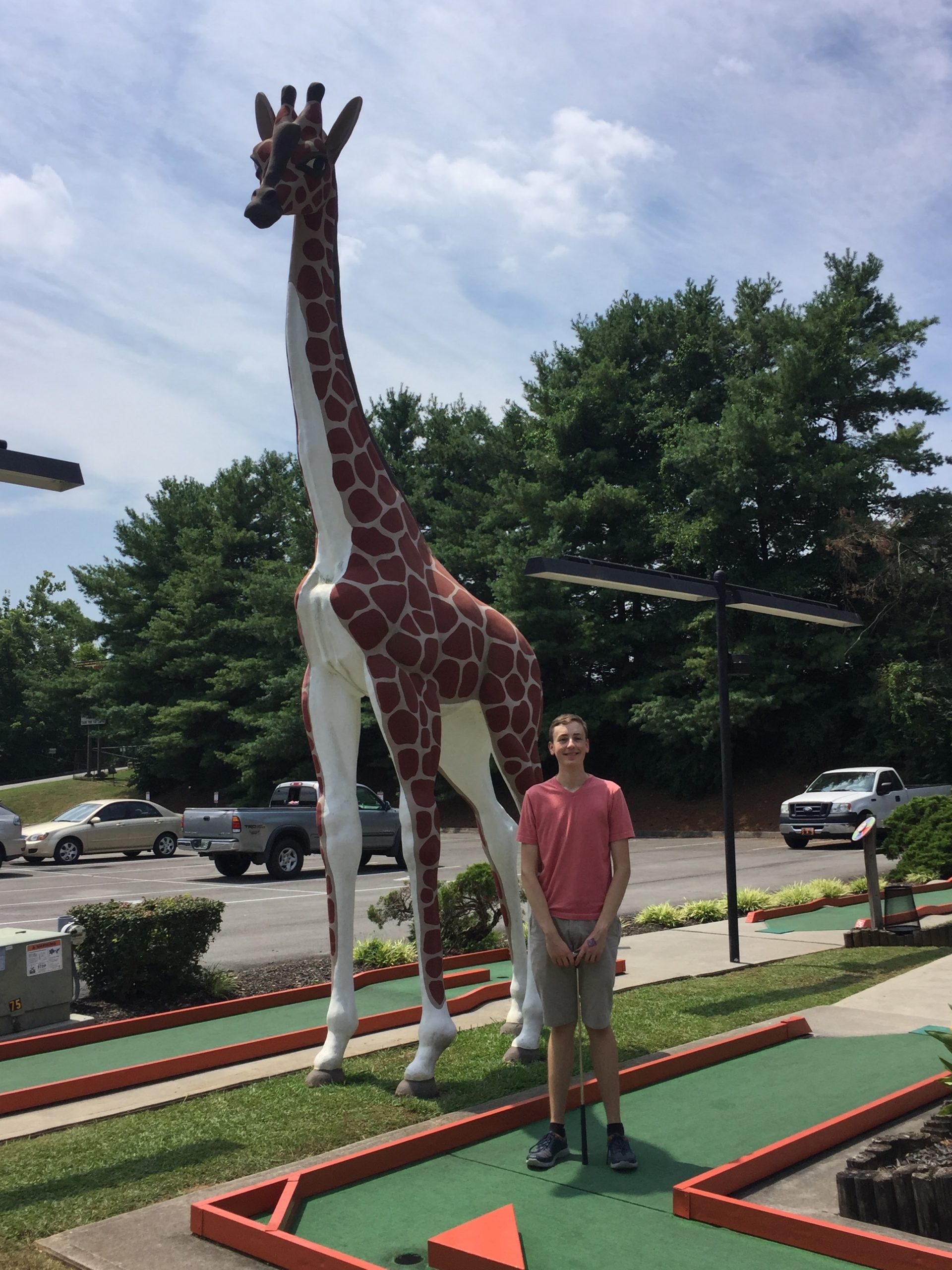 Zachary posing next to his giraffe dad